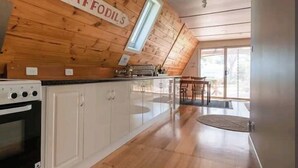 Une cuisine avec des murs en bois, une fenêtre et un coin repas comprenant une table et des chaises.