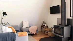 Un salon moderne avec un canapé gris, un lampadaire noir, une cheminée noire et un téléviseur à écran plat fixé au mur.