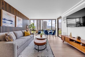 Una sala moderna con un sofá, una mesa de centro y sillas, un ventanal con vista a la ciudad y paneles de madera en la pared.