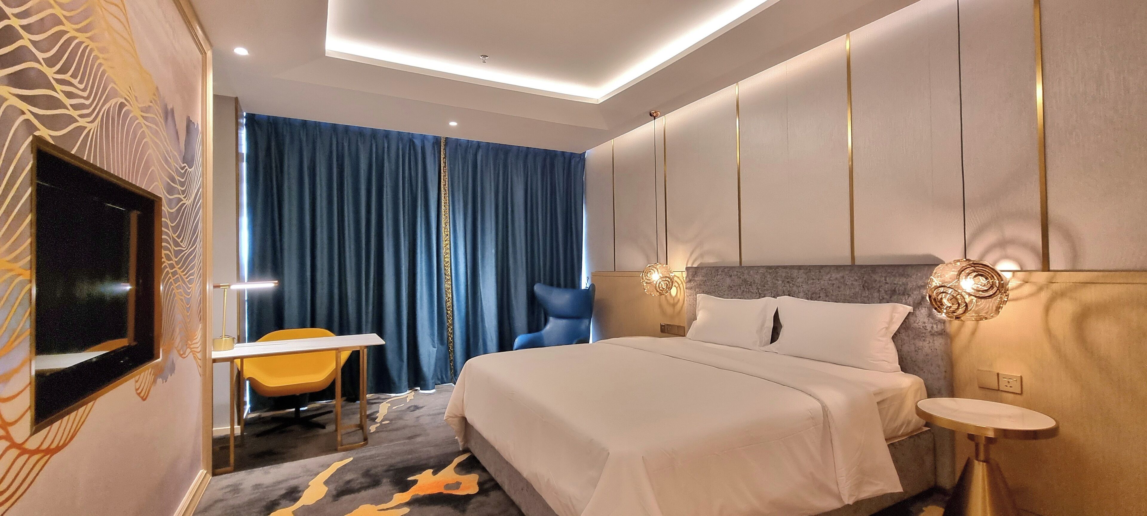 Una habitación de hotel moderna con una cama grande, un escritorio, una silla y un televisor.