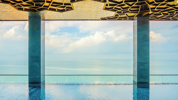 A pool with clear water, surrounded by glass railings and supported by large columns. - Won Majestic Hotel Cambodia (Sihanoukville)