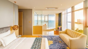 A hotel room with a bed, a sofa, a bathroom with a bathtub, and a view of the ocean. - Won Majestic Hotel Cambodia (Sihanoukville)