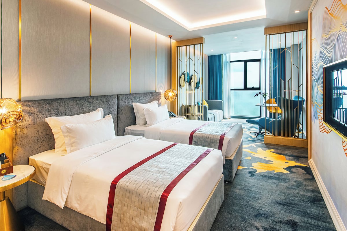A hotel room with two beds, a large mirror, and a view of the city.