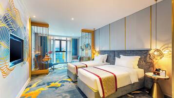 A hotel room with two beds, a TV, a bedside table, and a view of the city.