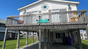 A two-story building with a balcony, a star decoration, and a sign with the number 6018. - Deep-Water Canal Front Coastal Cottage Only Steps to the Beach & Pet Friendly!  (Surf City)