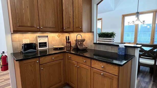 A modern kitchen with wooden cabinets, a black countertop, and a view of the outside. - Newly Renovated 4BR 2BA Ocean Block Bay View Ship Bottom Home Central Location  (Ship Bottom)