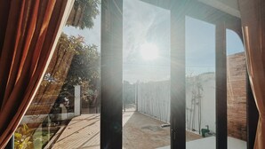 A modern interior with large glass doors leading to an outdoor area with a wooden deck and bamboo plants. - Xom House Bien Ho (Bien Ho)
