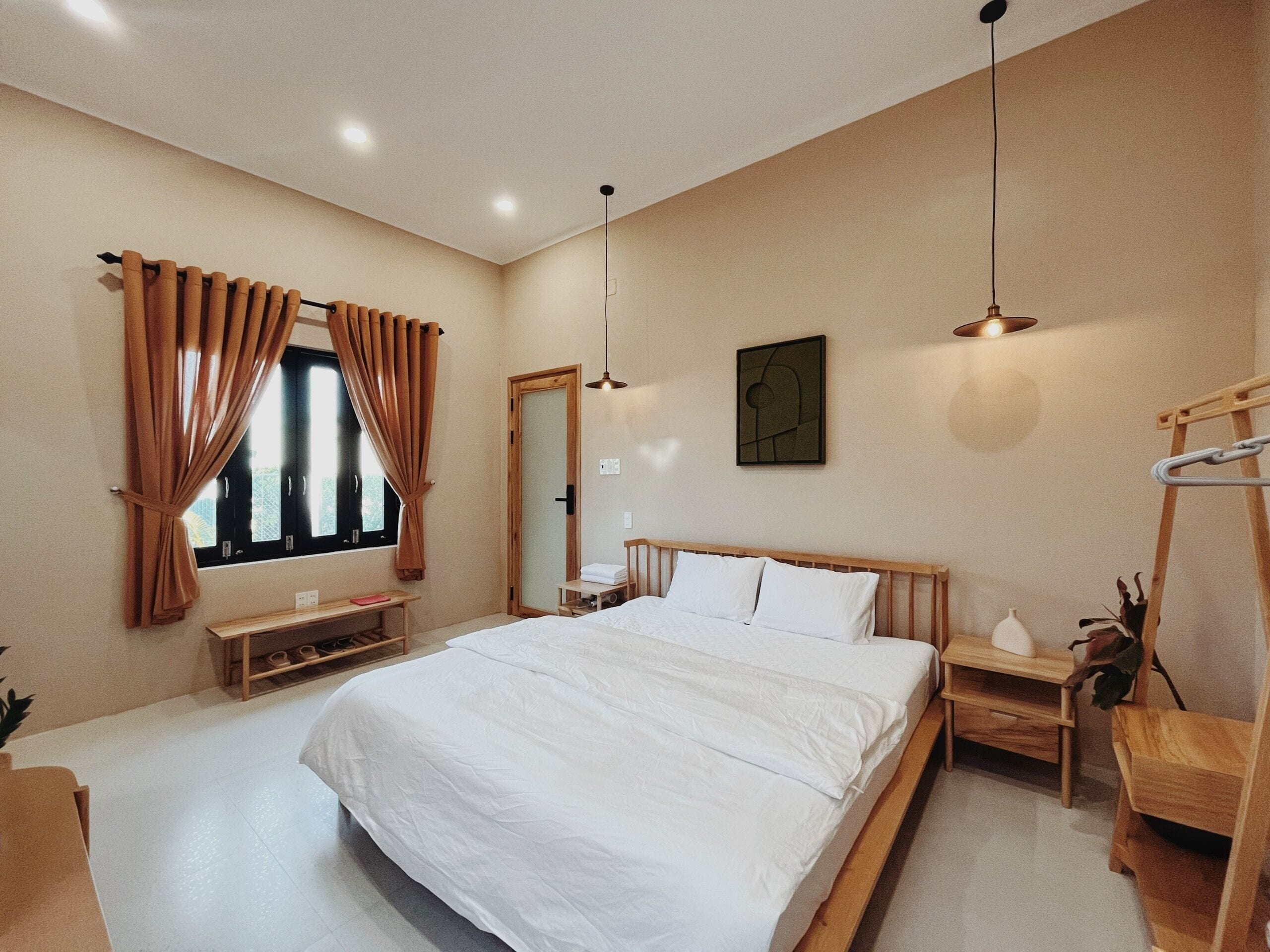 A bedroom with a large bed, wooden headboard, bedside tables, a desk, and a ladder.