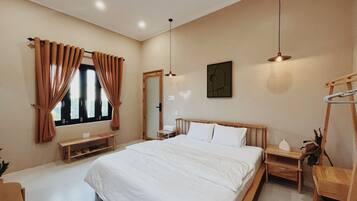 A bedroom with a large bed, wooden headboard, bedside tables, a desk, and a ladder.