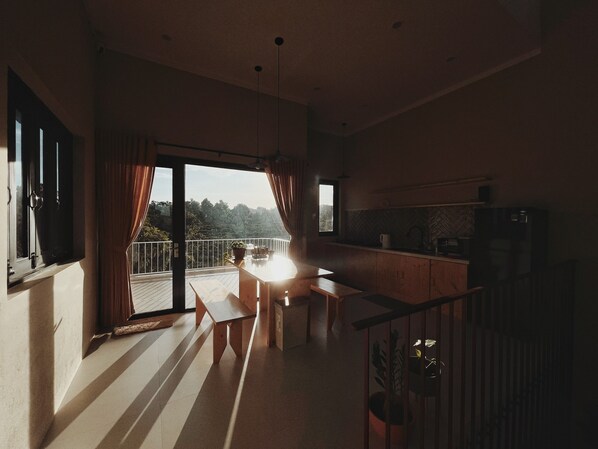 A modern kitchen with a dining area, large windows, and a view of the outdoors.