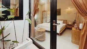 A modern bedroom with a glass door, a bed, a bedside table, and a hanging light fixture. - Xom House Bien Ho (Bien Ho)