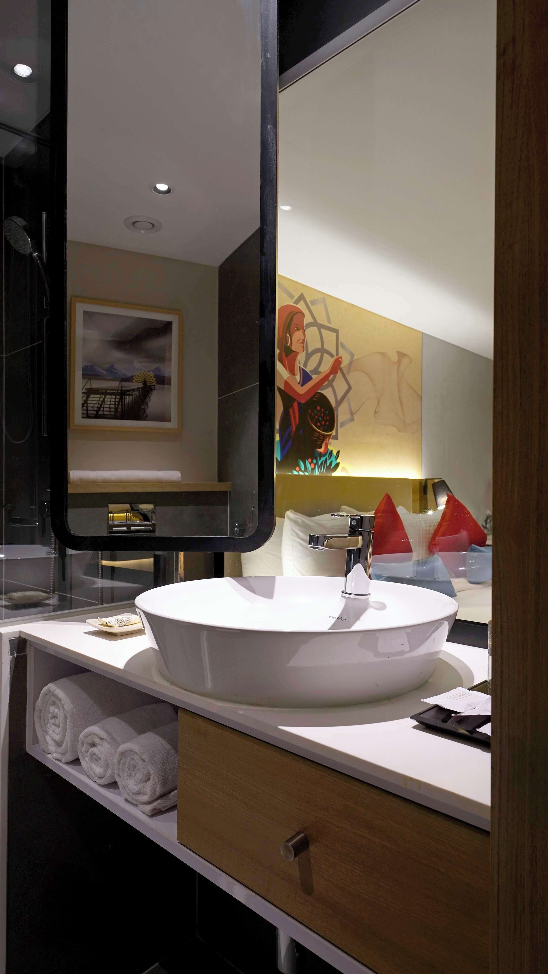 Un baño moderno con un espejo grande, un lavabo blanco y un perchero para toallas.