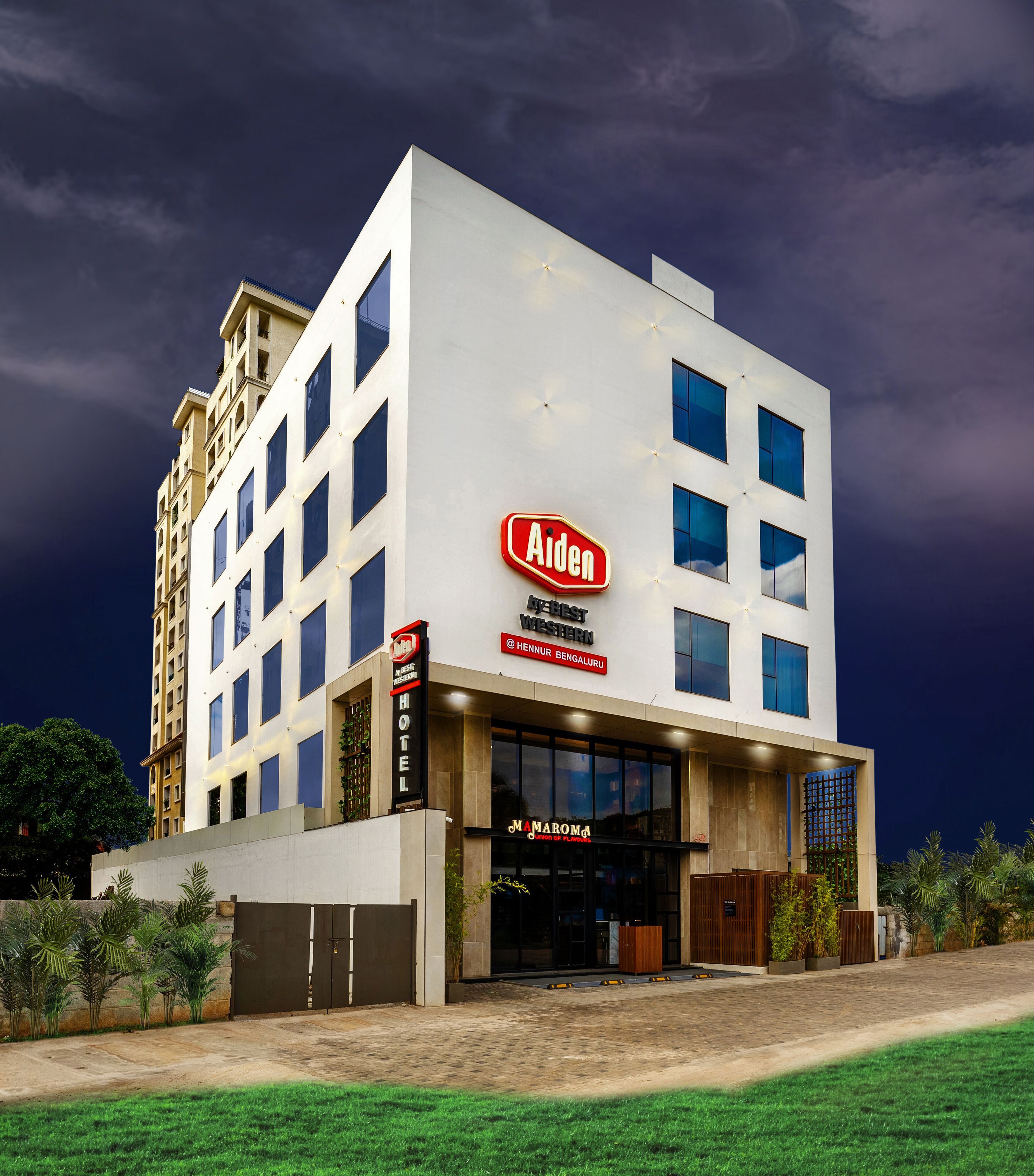 A modern hotel with a prominent 'Aiden' sign, a 'Best Western' logo, and a 'Mamarom' sign.