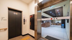 An elevator with a control panel and a door with a safety sign. - Haeundae Dongbeck Hotel (Busan)