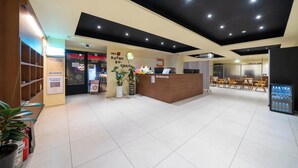 A hotel reception area with a reception desk, a clock, a plant, and a refrigerator. - Haeundae Dongbeck Hotel (Busan)