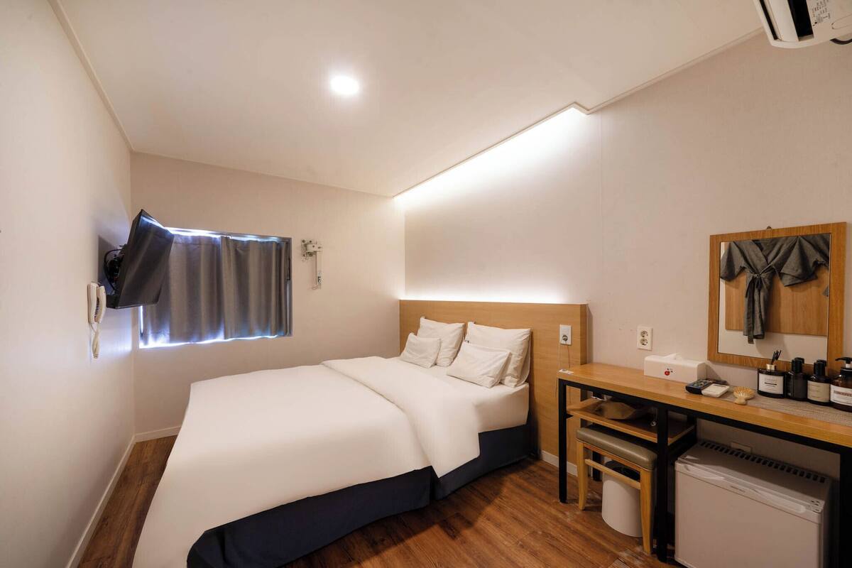 Una habitación de hotel con una cama, un escritorio con espejo, una mesita y un radiador.
