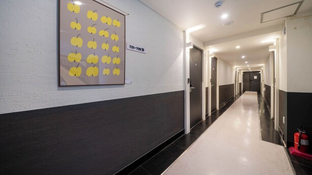 A hallway with a framed artwork of yellow cherries, a fire extinguisher, and a sign with a phone number. - Haeundae Dongbeck Hotel (Busan)