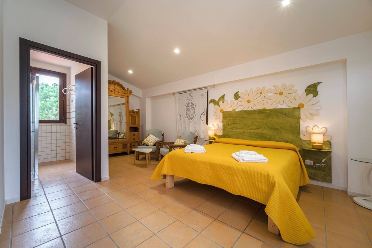 A bedroom with a bed, a chair, a table, and a window.