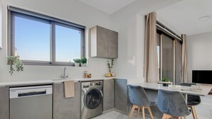 Une cuisine moderne équipée d’un lave-vaisselle, d’un lave-linge et d’un coin repas avec deux chaises et une table.