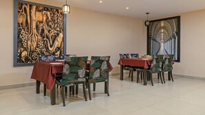 A dining area with a large wall mural, a view of a grand staircase, and a red tablecloth. - Itsy Hotels Kashi Grand, BHU (Varanasi)