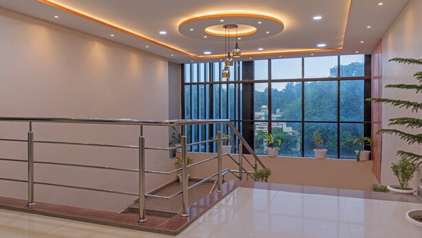 A modern hotel lobby with a staircase, large windows, and potted plants. - Itsy Hotels Kashi Grand, BHU (Varanasi)