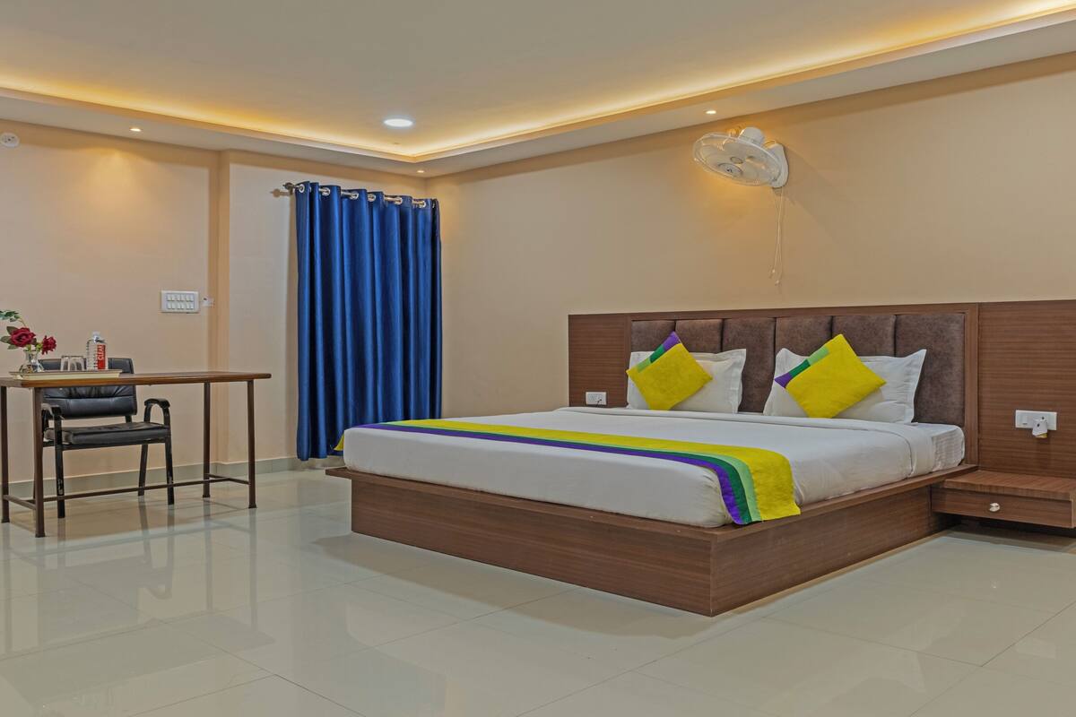 A modern hotel room with a large bed, bedside tables, a desk, and a chair.