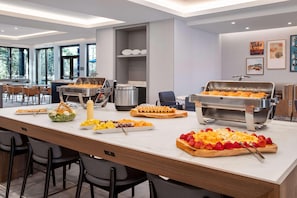 A buffet setup with various food items, a grill station, and a seating area with chairs.