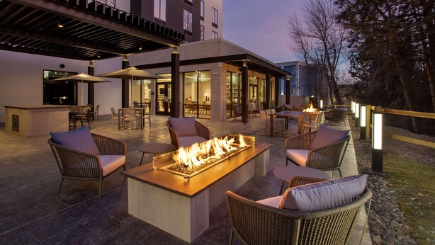Ein möblierter Außenbereich mit Terrasse, Feuerstelle, Korbmöbeln und einem überdachten Sitzbereich.