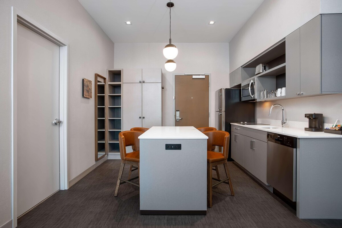 A modern kitchen with a central island, built-in appliances, and a dining area with chairs.