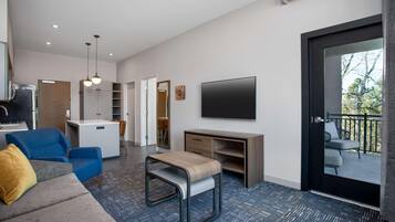 A modern living room with a sofa, a small table, a TV, and a balcony.