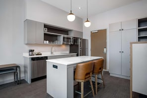 A modern kitchen with a central island, stainless steel appliances, and a seating area with two chairs. - (Missoula)