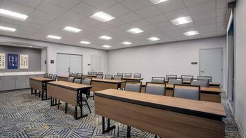 A conference room with multiple tables and chairs, a carpeted floor, and a whiteboard on the wall.