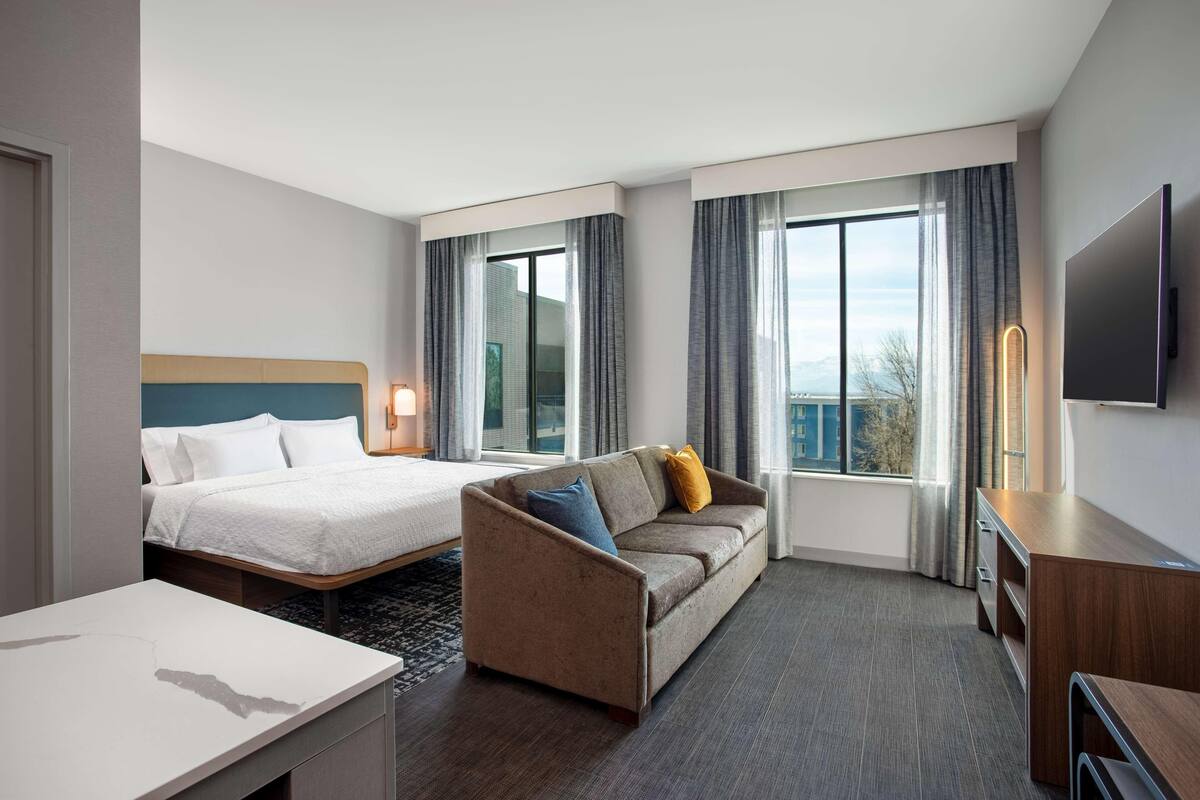 Una habitación de hotel con cama, sofá, televisión y escritorio.