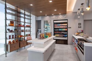 A modern hotel suite shop with a refrigerated display, snack bins, and a variety of beverages.