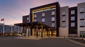 Ein Hotel im modernen Design, mit einem gut sichtbaren Schild für 'Homewood Suites by Hilton' und einem überdachten Eingang.