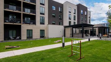 A multi-story building with balconies, a covered outdoor seating area, and a well-maintained lawn.