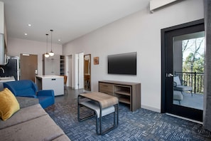 A modern living room with a sofa, a small table, a TV, and a balcony. - (Missoula)