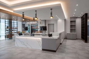 A modern hotel reception area with a marble counter, overhead lighting, and a visible minibar. - Homewood Suites by Hilton Missoula (Missoula)