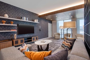 Un salon moderne avec un téléviseur à écran plat, des canapés, une table basse et un tapis à motifs.