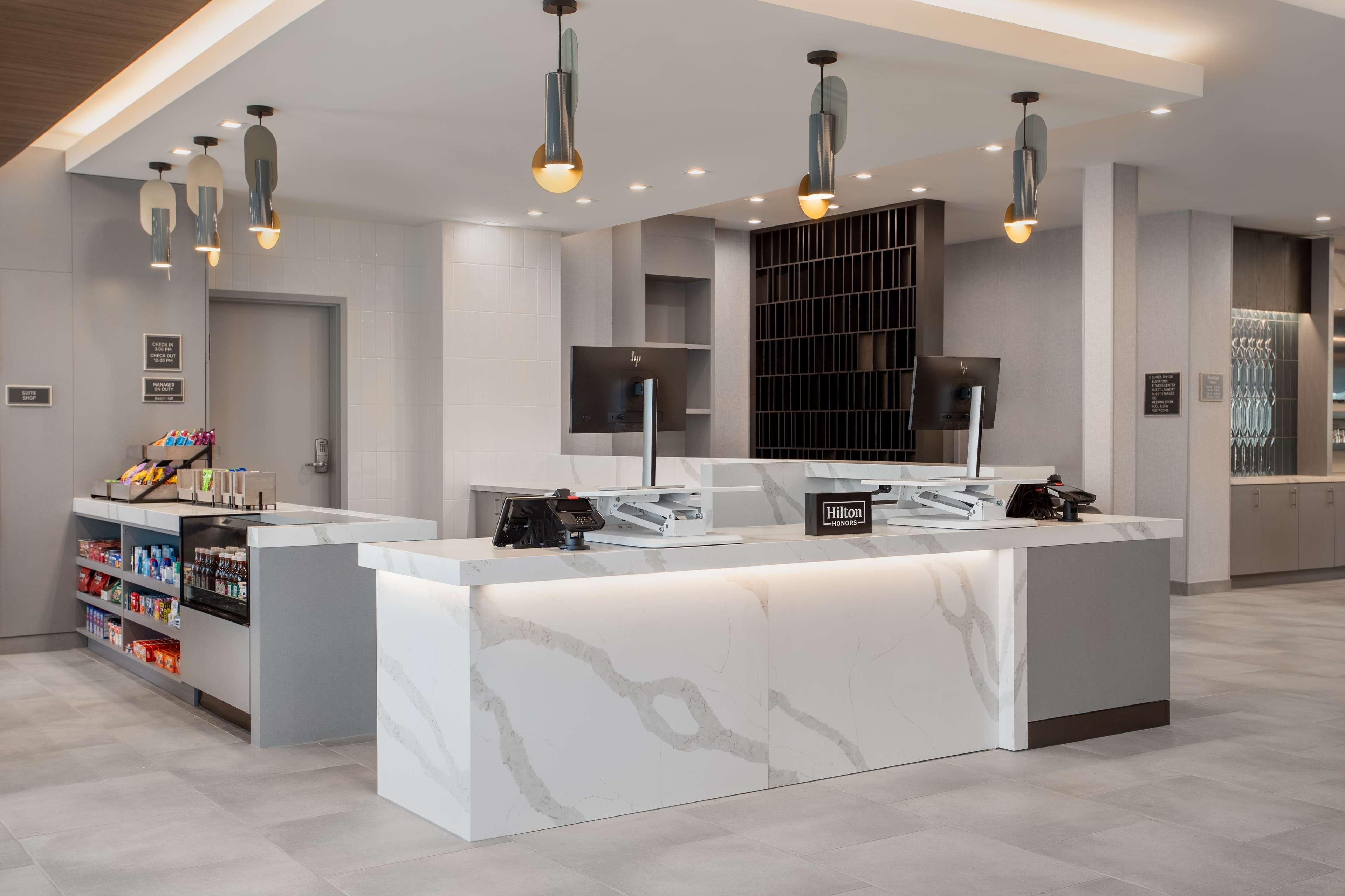 A modern hotel reception area with marble counters, a minibar, and pendant lighting.