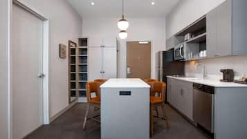 A modern kitchen with a central island, built-in appliances, and a dining area with chairs.