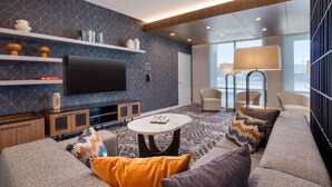 Ein modernes Wohnzimmer mit Flachbildfernseher, Sofas, Couchtisch und einem gemusterten Teppich.