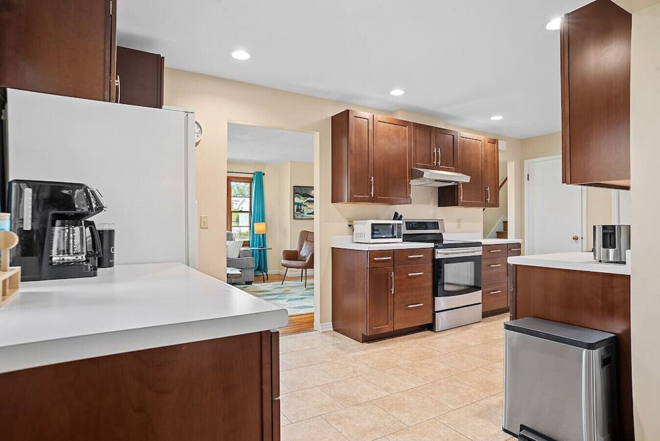A modern kitchen with wooden cabinets, a stainless steel refrigerator, a built-in oven, and a coffee maker.