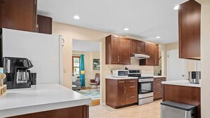 Una cocina moderna con armarios de madera, un refrigerador de acero inoxidable, horno empotrado y cafetera.