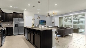 A modern kitchen with dark cabinets, stainless steel appliances, and a large island.
