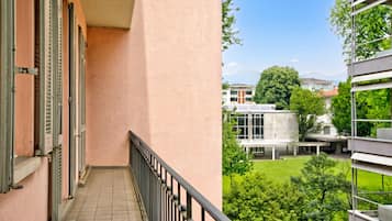 A balcony with a view of a building and a green area.