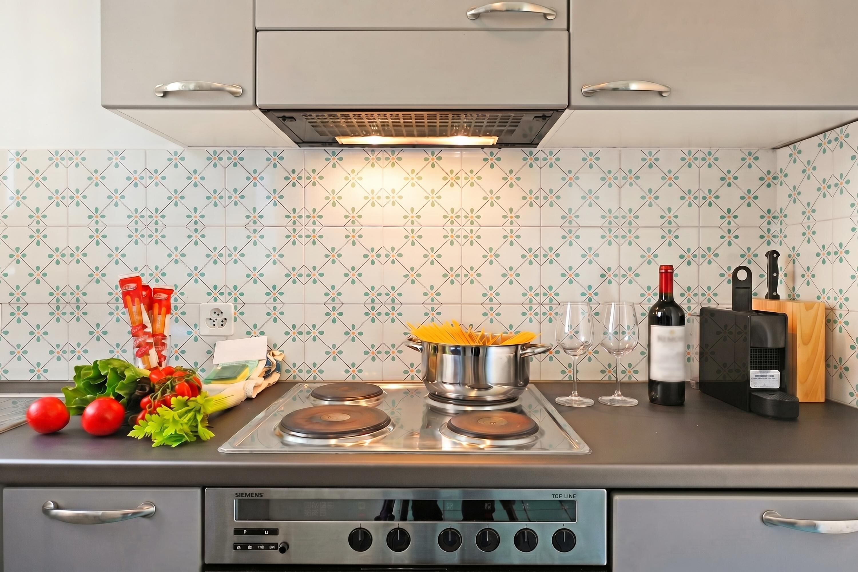 A kitchen with a Siemens stove, a wine bottle, and various food items.