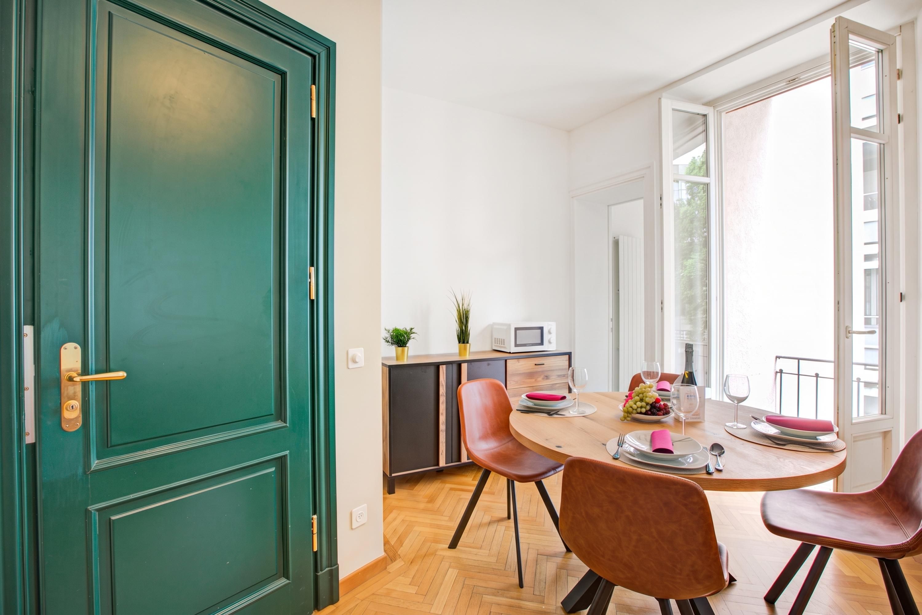 Un coin repas avec une table ronde, des chaises, un four à micro-ondes et une plante en pot.