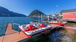 Un muelle con varios botes pequeños, un embarcadero de madera y un edificio de fachada roja.
