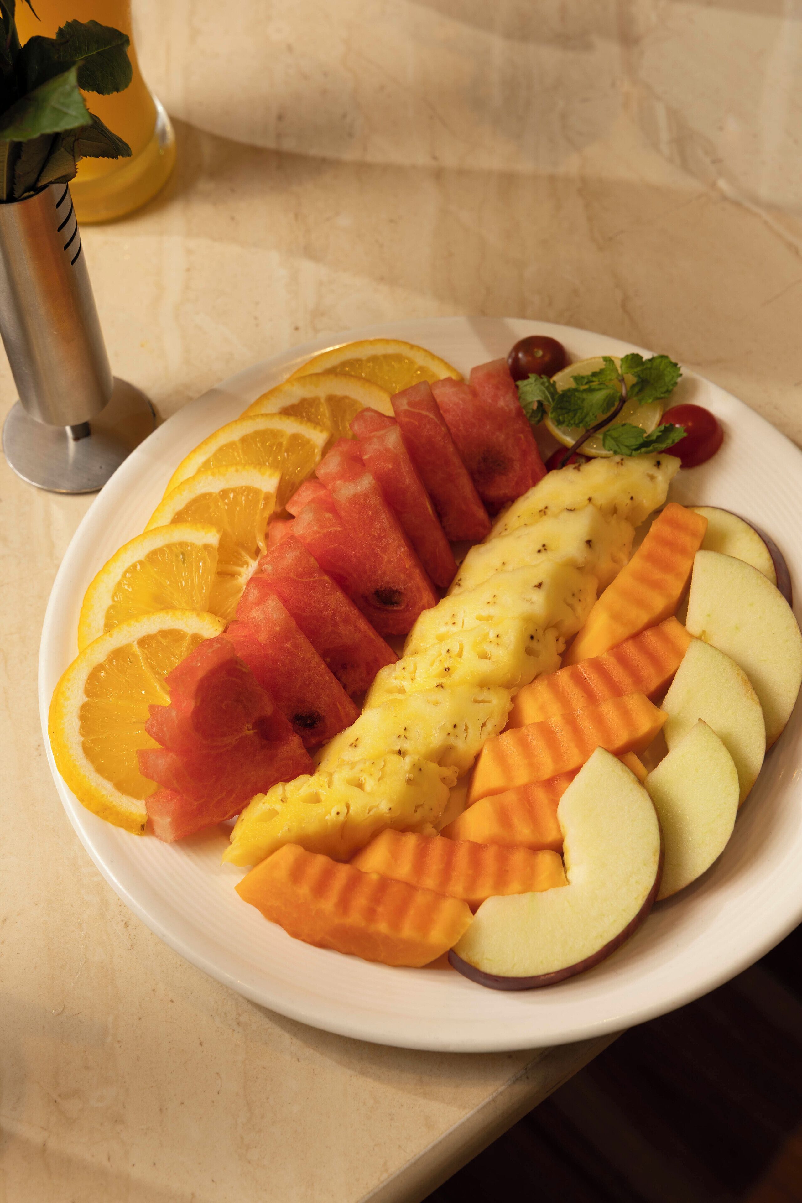 Un plato de frutas cortadas, entre ellas sandía, melón y manzanas.